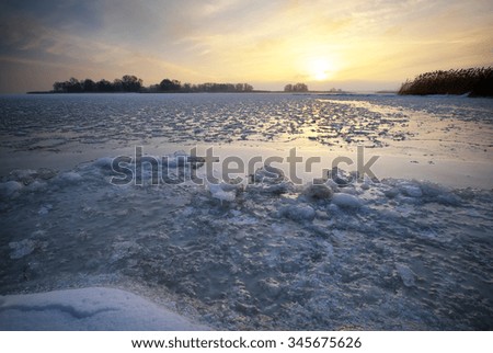 Winter landscape with frozen lake and sunset sky. Composition of nature.

