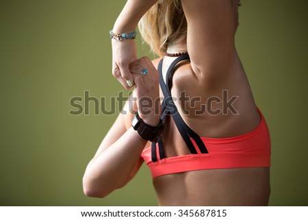 Sporty beautiful blond woman in sportswear working out indoors, doing Gomukhasana, Cow Face posture on orange eco mat, stretching triceps, shoulders, close up of arms, back view