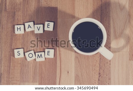 Have some coffee. An image of a coffee cup filled with black coffee and a text next to it made from plastic letters. Image has a coffee tone and vintage effect applied.