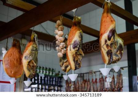 Picture of hanging down dry smoked jamon and garlic bunch on meat shop background