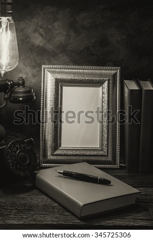 Still life of vintage telephone with picture frame and diary on table, Black and White image
