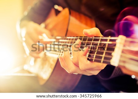 the young guy playing an acoustic guitar. Shooting backlit Royalty-Free Stock Photo #345725966
