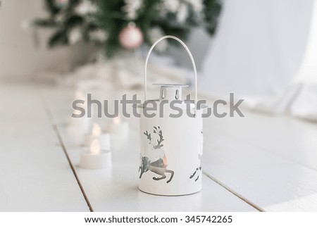 white vintage lantern with burning candles, deer, christmas tree on wooden floor