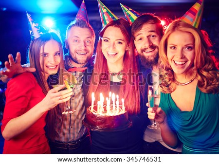 Joyful friends with cake enjoying birthday party
