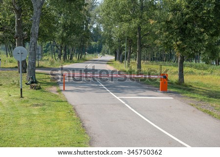 Rural road in the forest with closed red white barrier