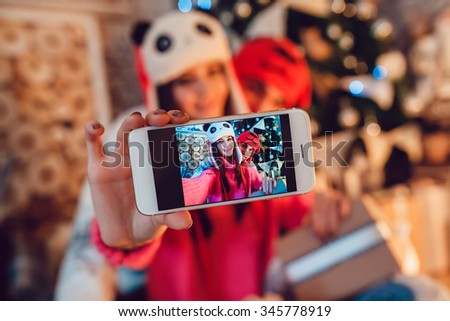  Loving couple dressed in funny hats doing selfie. Christmas decorations.