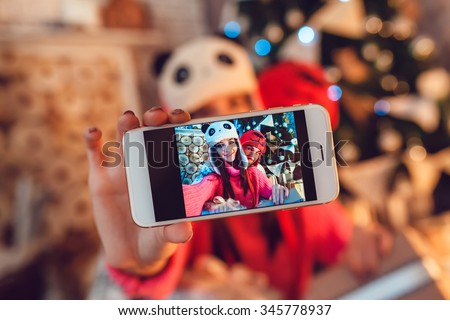  Loving couple dressed in funny hats doing selfie. Christmas decorations.