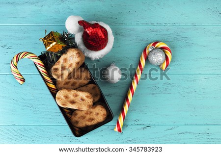 On the desktop background Christmas composition of mint blue metal box with cookies, a branch of spruce tree, gift, candy cane, Christmas balls. cap of Santa Claus