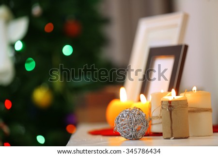 Candles and frames on fireplace in decorated Christmas room, close up