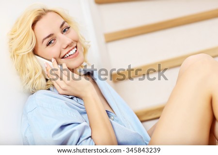 A picture of a young woman talking on the phone at home