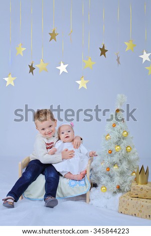Twinkle, twinkle, little star. Little 8 month toddler girl on a small bed under the star decorations near the Christmas tree with gifts and crown. Scandinavian christmas decor