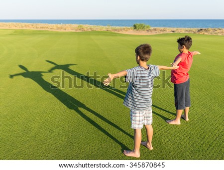 Kids with their shadows on grass