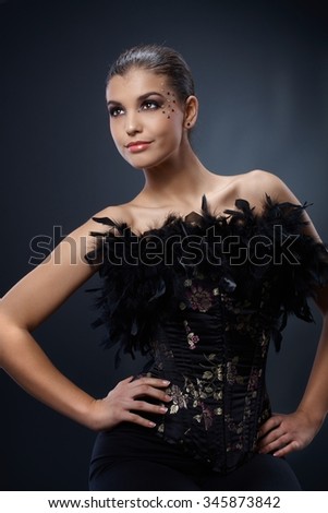 Attractive woman posing in black party dress with boa, luxury makeup, smiling.