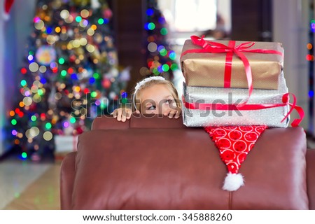 Happy smiling toddler child girl ready to get her Christmas presents and make wish on New Year Eve, xmas tree on background