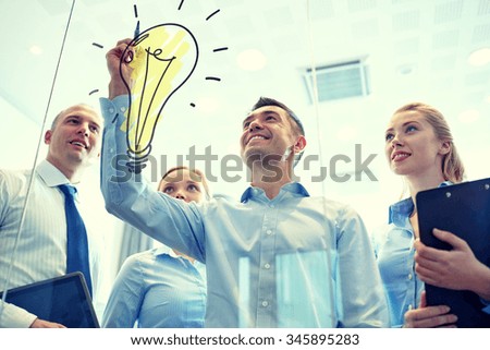 business, people, teamwork and planning concept - smiling business team with marker and light bulb doodle working in office