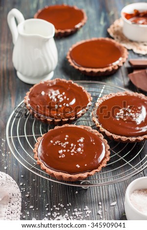 chocolate tarts with salted caramel on a dark wooden background in rustic style