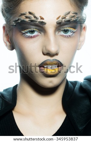 Closeup portrait of one beautiful wild young woman with bright golden animal monkey makeup with thorns on face in studio on white background, vertical picture