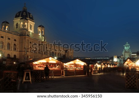 Photo of snowless evening Christmas market square with wooden stalls with holiday decorative illumination lighting in city centre streetscape over dark blue sky background, horizontal picture