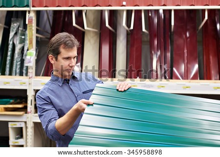 Man chooses metal profile for fence in construction store