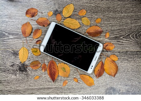 White modern tablet pc with blank empty screen on rustic vintage wood background with autumn leaves. Concept of season and technology, nature and computrs design template with place for image and text