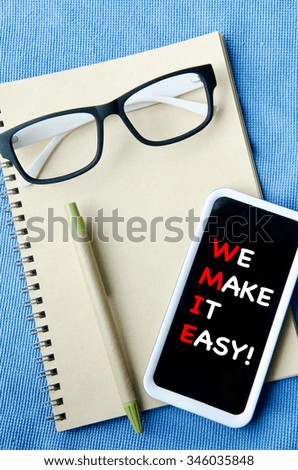 Office supplies Notebook paper smartphone and glasses . With we make it easy massage on screen