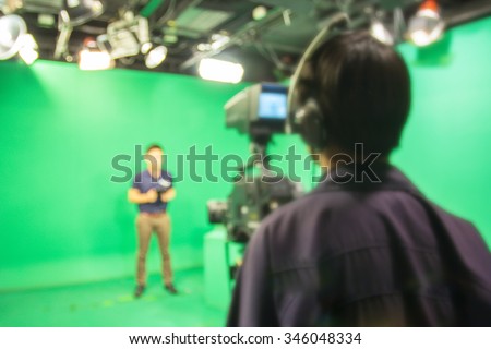 blur image A television presenter in a TV camera in studio a green