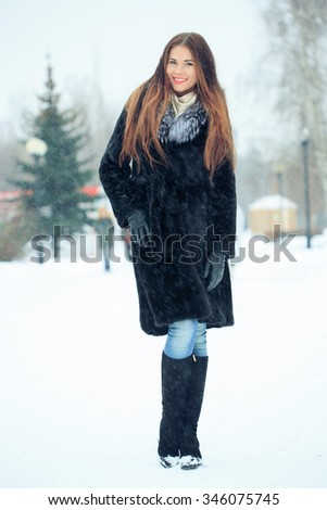 beautiful smiling girl on background of snowy trees. Winter portrait. coat with a hood. snowfall