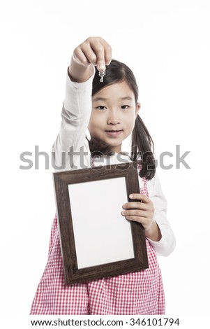 A asian(korean, japanese, chinese) girl(kid, student, child, woman, female) wearing red shirts and denim pants stand up with a wood photo frame and key for friend and family isolated white.