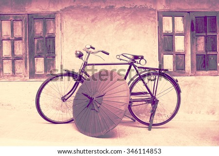 a graphic color of an old fashioned bicycle and vintage northern Thai umbrella in an old background