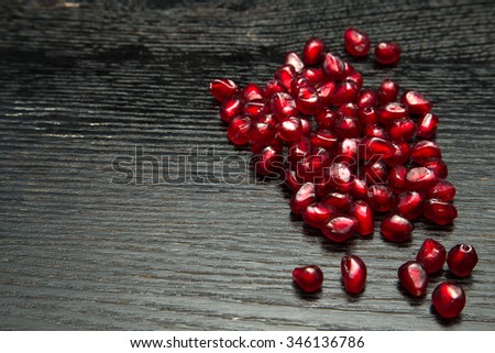 Juicy ripe pomegranate fruit on a black wooden table for background. Selective focus.