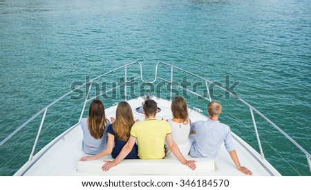 Group of young people siting  and looking outside from yacht. Back view. Royalty-Free Stock Photo #346184570