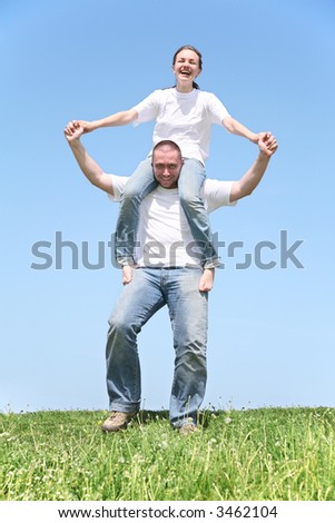 girl on boy's shoulders on grass