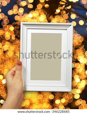 Wooden frame in beautiful woman hands on the background christmas bokeh