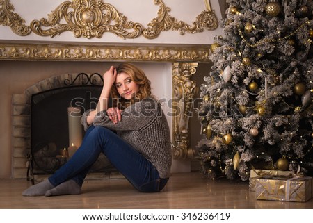 Close-up portrait of young blonde girl in grey pullover over christmas background