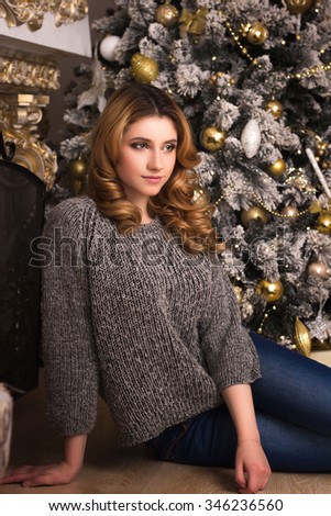 Close-up portrait of young blonde girl in grey pullover over christmas background