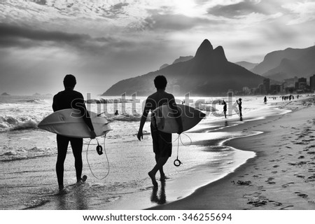 Scenic black and white view of Rio de Janeiro, Brazil with Brazilian surfers walking along the shore of Ipanema Beach