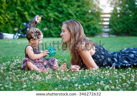 beautiful little girl walks on the grass in the summer with my mother.