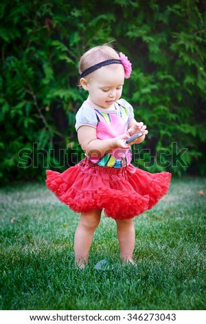 little girl with a phone in a red skirt.