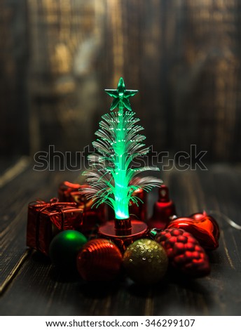 small Christmas tree  led lighting around  with small Christmas ornament  on the dark wooden table background.