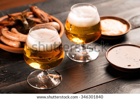 Two glasses of beer on the black table with snacks Royalty-Free Stock Photo #346301840