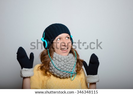 a young girl listening to music on headphones, bright yellow winter photo in studio shot isolated on gray background