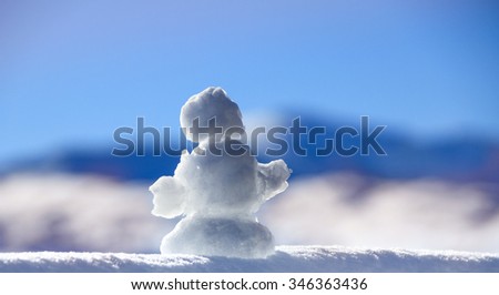 Snowman against snowy winter mountains