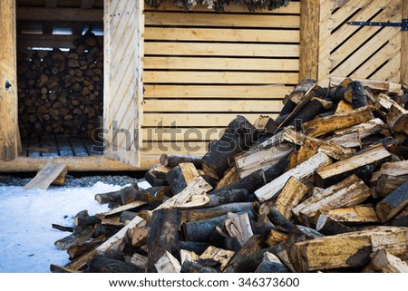Lots of firewood lying on the street randomly scattered in the background house with folded it with firewood