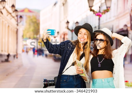 Two happy girls taking selfies with mobile phone