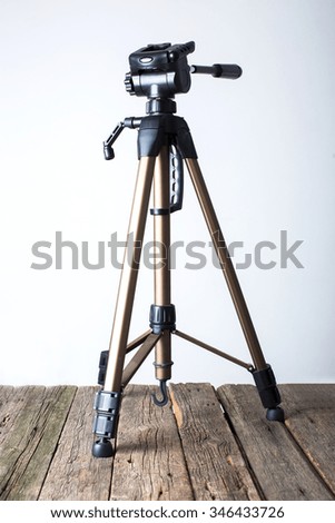 Photographers tripod on white and wooden background