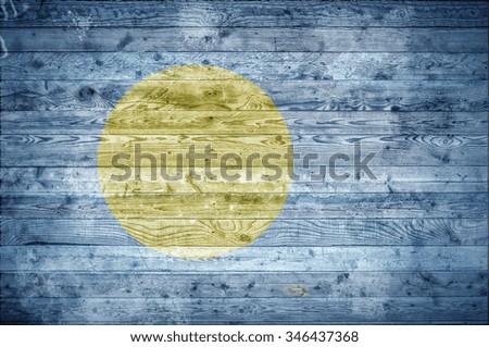 A vignetted background image of the flag of Palau onto wooden boards of a wall or floor.