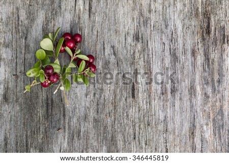 Fresh ripe cranberries with leaves lying on the old vintage wooden table. Background for nature themes. Horizontal overhead view.