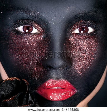 Beauty portrait of woman with creative makeup. Black mask. Brown eyes. Girl looking at camera.