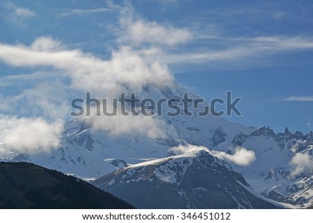 Snow-capped mountain in the clouds Kazbek at dawn, Georgia