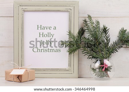 Have a Holly Jolly Christmas  poster in  shabby chick frame,  Fir branch and vintage gift box with with copy space blank tag on white background. Scandinavian style home interior decoration